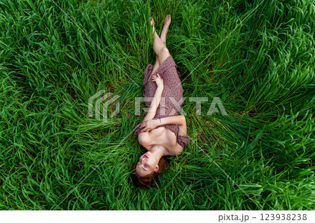 A young girl in a beautiful dress lies in the green grass A young girl in a beautiful dress lies in the green grass 123938238