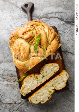 Homemade bread is braided with basil pesto closeup on the wooden board. Vertical top view Homemade bread is braided with basil pesto closeup on the wooden board. Vertical top view 123938808