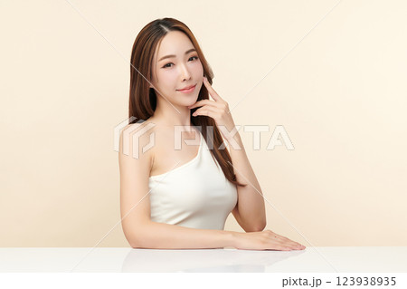 A beautiful young Asian woman with clean, fresh skin against a beige background. She represents beauty, skincare, and spa treatments. A beautiful young Asian woman with clean, fresh skin against a beige background. She represents beauty, skincare, and spa treatments. 123938935
