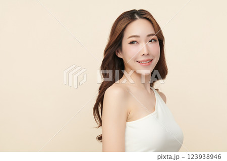 A beautiful young Asian woman with clean, fresh skin against a beige background. She represents beauty, skincare, and spa treatments. 123938946
