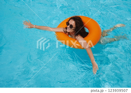 young beautiful girl swimming in an inflatable circle in pool at a hotel on vacation at a resort in summer holidays young beautiful girl swimming in an inflatable circle in pool at a hotel on vacation at a resort in summer holidays 123939507