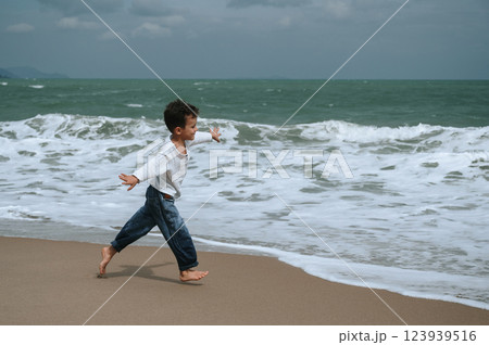 happy child boy running along beach by sea in summer on vacation 123939516