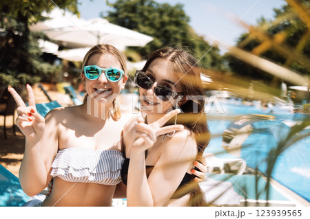 Two cute teenagers in swimsuits are laughing in the pool. Smiling female friend 123939565