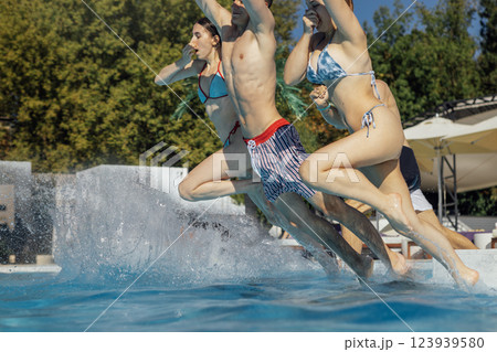 Cute teens in swimsuits jump into the pool. Joyful boys and girls dive into the clear water. Cute teens in swimsuits jump into the pool. Joyful boys and girls dive into the clear water. 123939580