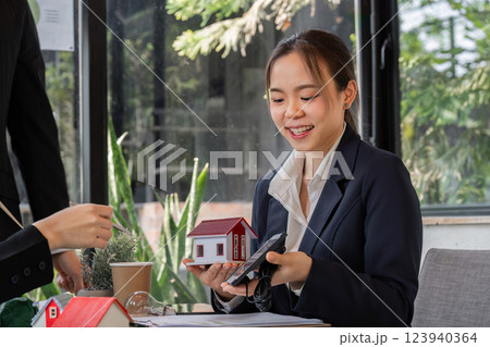 Sustainability and Innovation. A young professional presenting a model of an eco-friendly house during a meeting. Sustainability and Innovation. A young professional presenting a model of an eco-friendly house during a meeting. 123940364