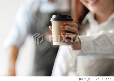 Sustainable Coffee and Personal Touch. A barista proudly presents a takeaway coffee cup to a satisfied customer. Sustainable Coffee and Personal Touch. A barista proudly presents a takeaway coffee cup to a satisfied customer. 123940377