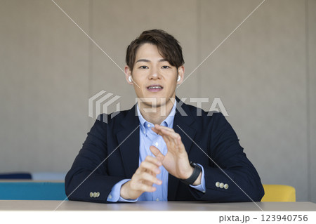 カメラ目線で話すイヤホンをつけた30代の男性 カメラ目線で話すイヤホンをつけた30代の男性 123940756