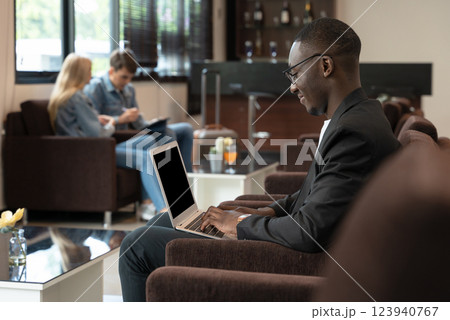 African businessman working on laptop while waiting for his flight at airport lounge African businessman working on laptop while waiting for his flight at airport lounge 123940767