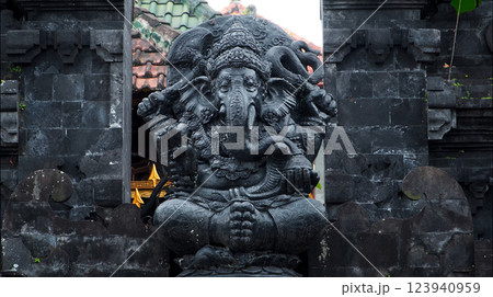 An old hindu stone statue of Ganesha covered with moss, standing on the str.. 123940959