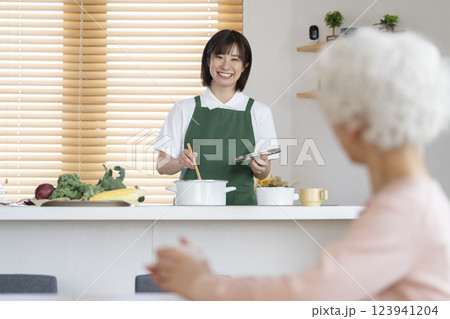 家事代行イメージ　キッチンで料理をする30代の女性とシニア女性  123941204