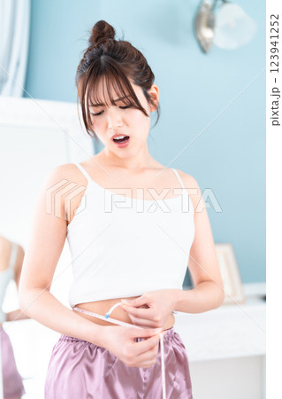 ウェストを測って驚く若い女性 123941252