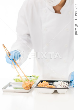 食品工場で御惣菜を詰める若い女性 顔無し 食品工場で御惣菜を詰める若い女性 顔無し 123941286