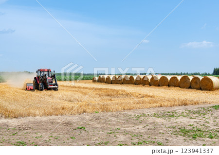 夏の北海道 麦稈ロールと作業中の機械(北海道イメージ) 夏の北海道 麦稈ロールと作業中の機械(北海道イメージ) 123941337