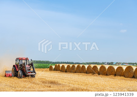 夏の北海道　麦稈ロールと作業中の機械（北海道イメージ） 123941339