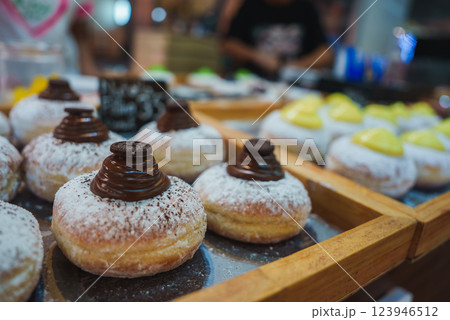 Trays of powdered sugar coated donuts with chocolate swirls and cream fillings, displayed in a bakery or market setting in Thailand. 123946512