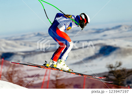 ski racer perform jump during competitive alpine skiing in snowy mountain landscape 123947197