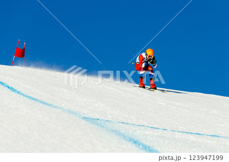 skier in bright gear down snow-covered slope marked with flags during competitive alpine skiing skier in bright gear down snow-covered slope marked with flags during competitive alpine skiing 123947199