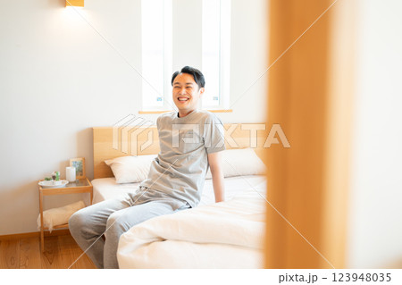 ベッドに座るパジャマ姿の男性 123948035