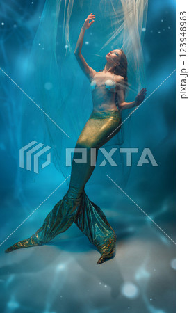 Graceful, elegant young woman, mermaid surrounded by delicate veils, floating in a dreamlike atmosphere Graceful, elegant young woman, mermaid surrounded by delicate veils, floating in a dreamlike atmosphere 123948983