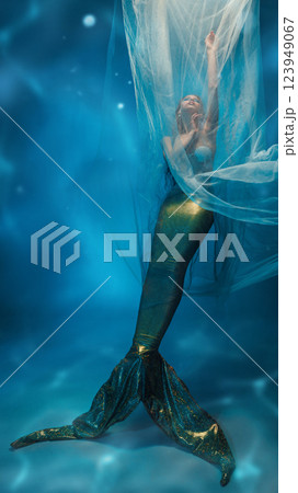 Tender young woman, mermaid covered in transparent veil, dancing towards glowing light above with eyes closed 123949067