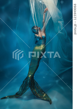 Tender and graceful young woman, mermaid with sparkling tail immersed in tender dance, covered in transparent vails, eyes close 123949068