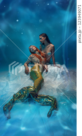 Mysterious vibe of relaxation. Two young beautiful women, mermaids with sparkling tails and pearl accessories enjoying calmness 123949071