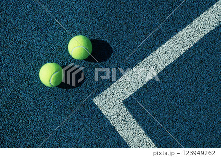 Two tennis balls with white lines on blue tennis court with artificial covering. View from above. Sports background. Two tennis balls with white lines on blue tennis court with artificial covering. View from above. Sports background. 123949262