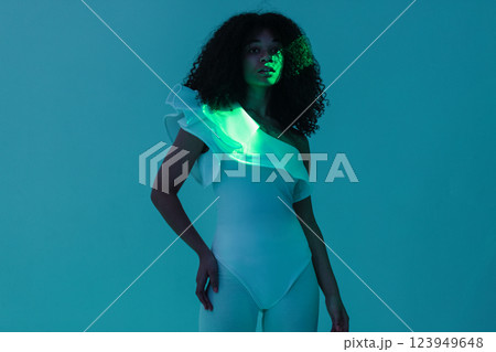 An African in a white outfit stands with her hand raised on a turquoise background 123949648