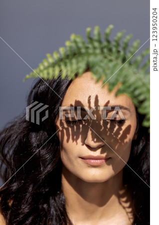 A close-up beauty portrait of a young attractive woman with closed eyes and a green leaf A close-up beauty portrait of a young attractive woman with closed eyes and a green leaf 123950204