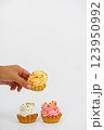 Three shortbread cakes with cream. One cake in a woman's hand. White background. 123950992