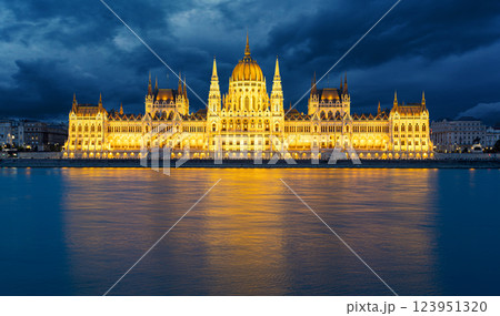 Hungarian parliament building reflecting on danube river at dusk with dramatic sky Hungarian parliament building reflecting on danube river at dusk with dramatic sky 123951320