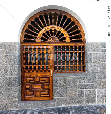 Elegant wooden door and transom with ornate carvings in stone wall Elegant wooden door and transom with ornate carvings in stone wall 123951361