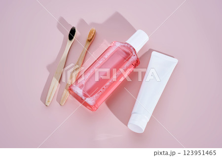Pink mouthwash, toothpaste and toothbrushes on a pink background. 123951465