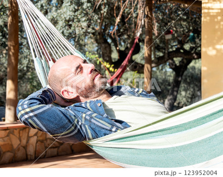 Man relaxing in a hammock outdoors on a sunny day. 123952004