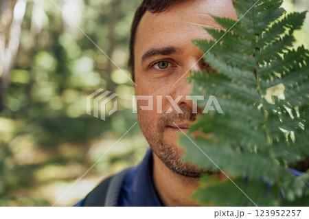 Close-up portrait of young happy man with fern in nature. 123952257
