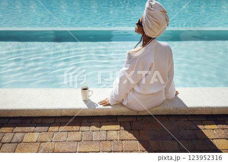 Young pretty woman in a white bathrobe holds a cup of coffee. Young pretty woman in a white bathrobe holds a cup of coffee. 123952316
