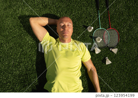 Badminton athlete or player resting after game, lying and enjoy on sport court in public park with artificial turf as green grass. Outdoors. Summer sports game. View from above 123954199
