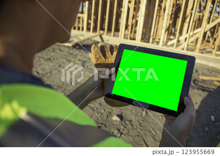 Female Construction Worker At Construction Site Holding Computer Tablet With Green Screen. 123955669