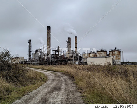 An industrial refinery with numerous smokestacks emitting thick black and gray smoke, indicating heavy pollution. The scene highlights environmental concerns related to industrial emissions. 123955904