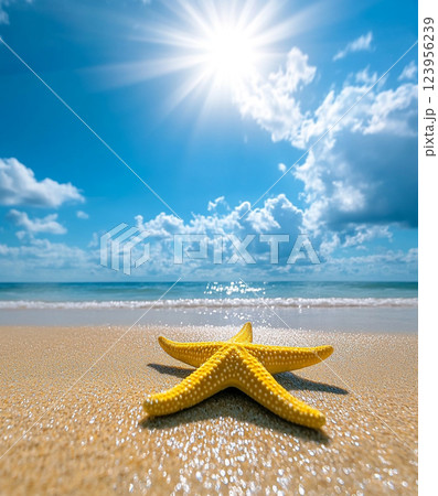 A vibrant yellow starfish with white spots rests on a sandy beach under a bright blue sky with scattered clouds and sunlight. 123956239
