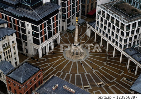 Aerial view captures a modern urban plaza with a central monument and geometric pathways. Surrounding buildings display contemporary architectural styles, creating a vibrant city atmosphere. Aerial view captures a modern urban plaza with a central monument and geometric pathways. Surrounding buildings display contemporary architectural styles, creating a vibrant city atmosphere. 123956897