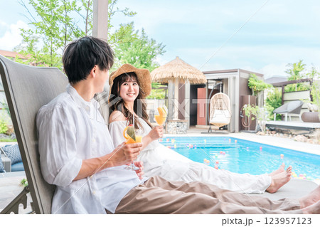 旅行でリゾートホテルのプールサイドに座るカップル・夫婦 旅行でリゾートホテルのプールサイドに座るカップル・夫婦 123957123