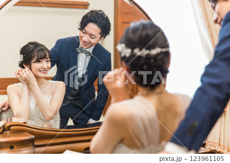結婚式・披露宴の支度をする笑顔の新郎新婦（ブライダルジュエリー・アクセサリー） 123961105