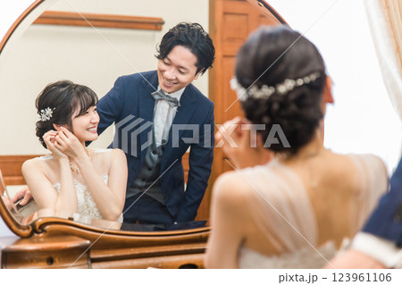 結婚式・披露宴の支度をする笑顔の新郎新婦（ブライダルジュエリー・アクセサリー） 123961106