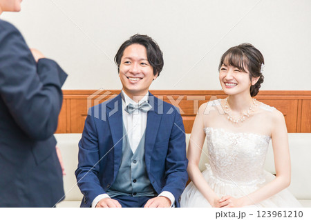 結婚式場の控え室にいる新郎新婦とウェディングプランナー・コンシェルジュの女性スタッフ 123961210