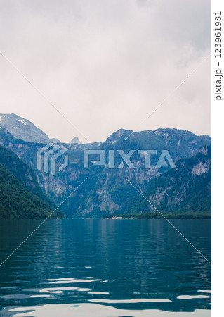 A stunning view of a lush green forest surrounded by towering mountain peaks. The serene landscape evokes a sense of peace and natural beauty, perfect for nature enthusiasts. Konigssee lake Bavaria 123961981