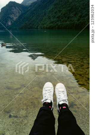 white shoe A stunning view of a lush green forest surrounded by towering mountain peaks. The serene landscape evokes a sense of peace and natural beauty, perfect for nature enthusiasts. Konigssee lake 123962034
