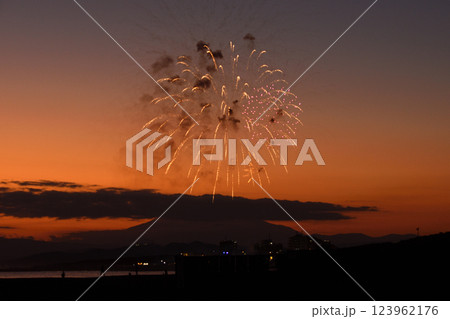夕焼けの富士山のシルエットをバックに打ち上げられる花火 123962176