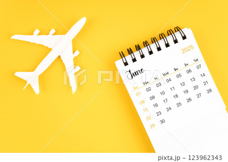 June 2025 calendar and airplane toy on yellow background. June 2025 calendar and airplane toy on yellow background. 123962343