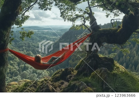 A traveler relaxing in a hammock tied between two trees, gazing at the vast mountain landscape. 123963666